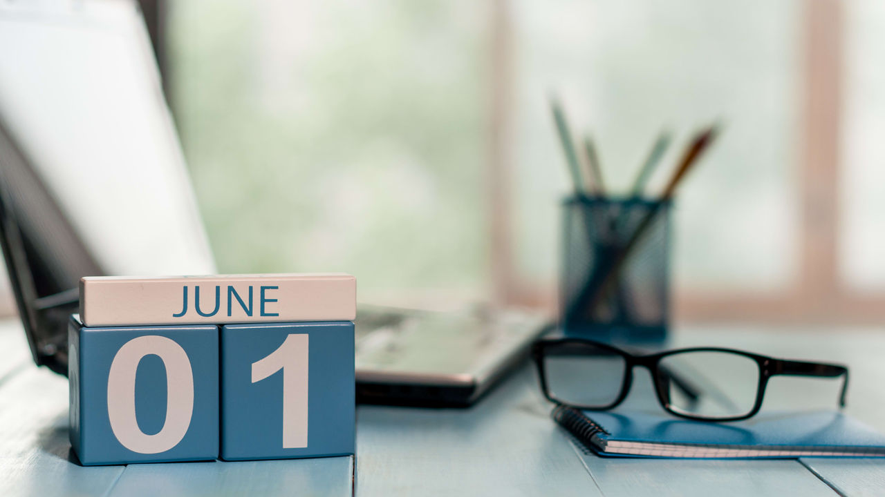 A calendar with the word june on it sits on a desk.