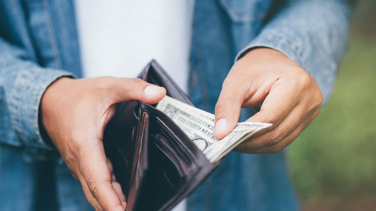 A man is holding a wallet full of money.