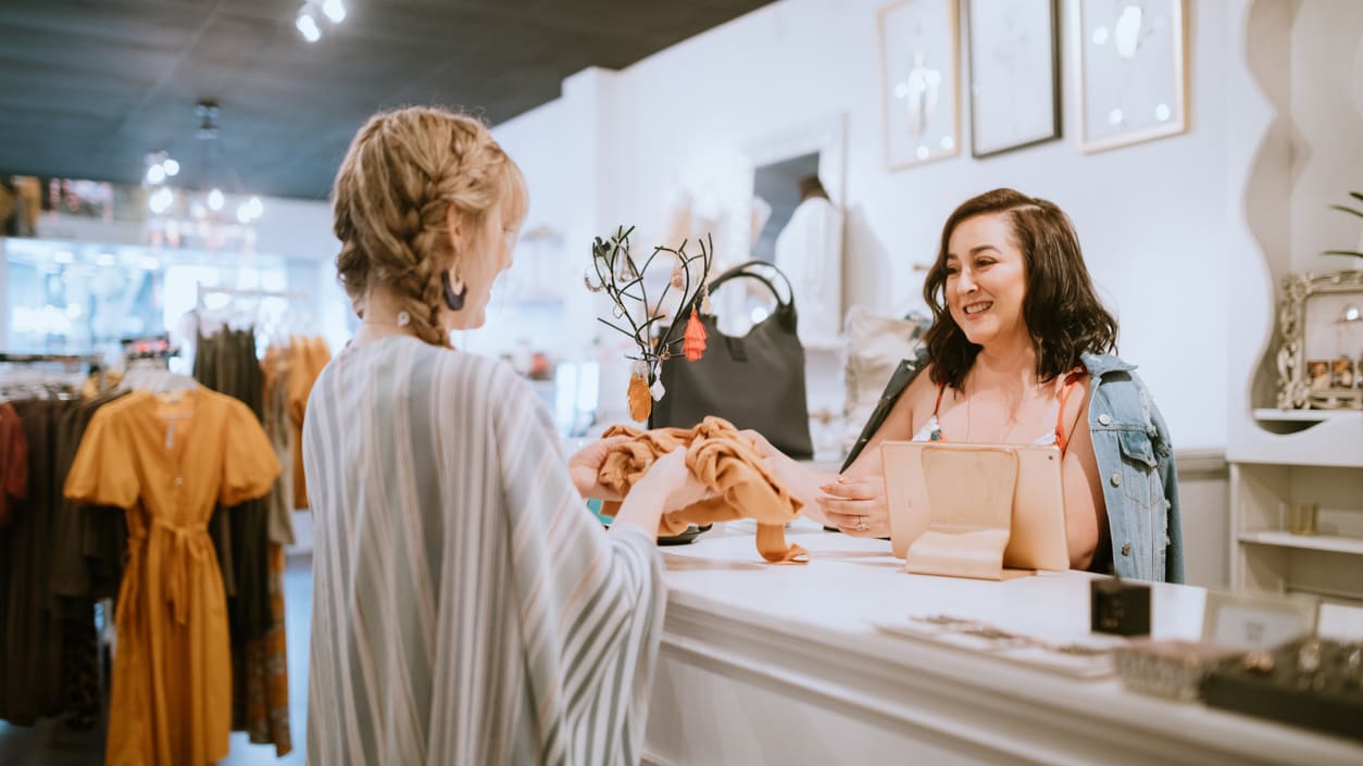 A woman is standing at the counter of a clothing store.