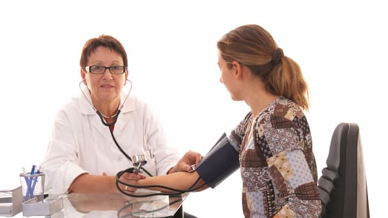 A doctor is taking a woman's blood pressure.