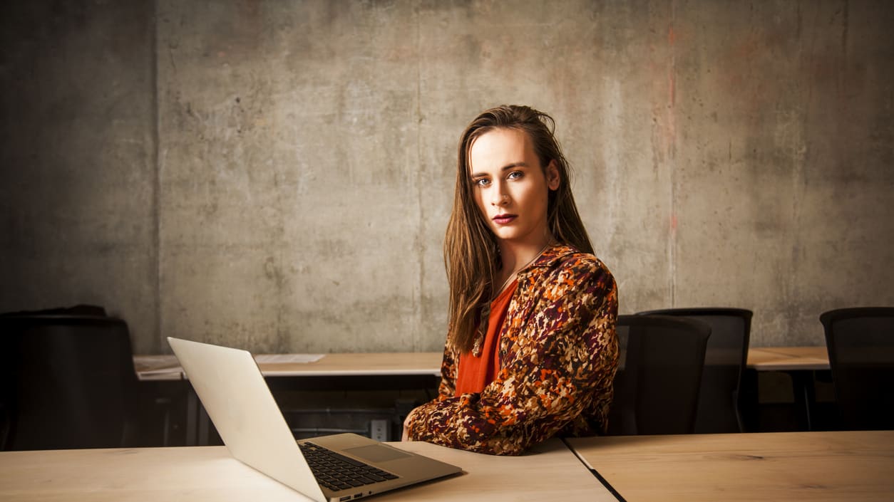 A young woman sitting at a desk with a laptop.