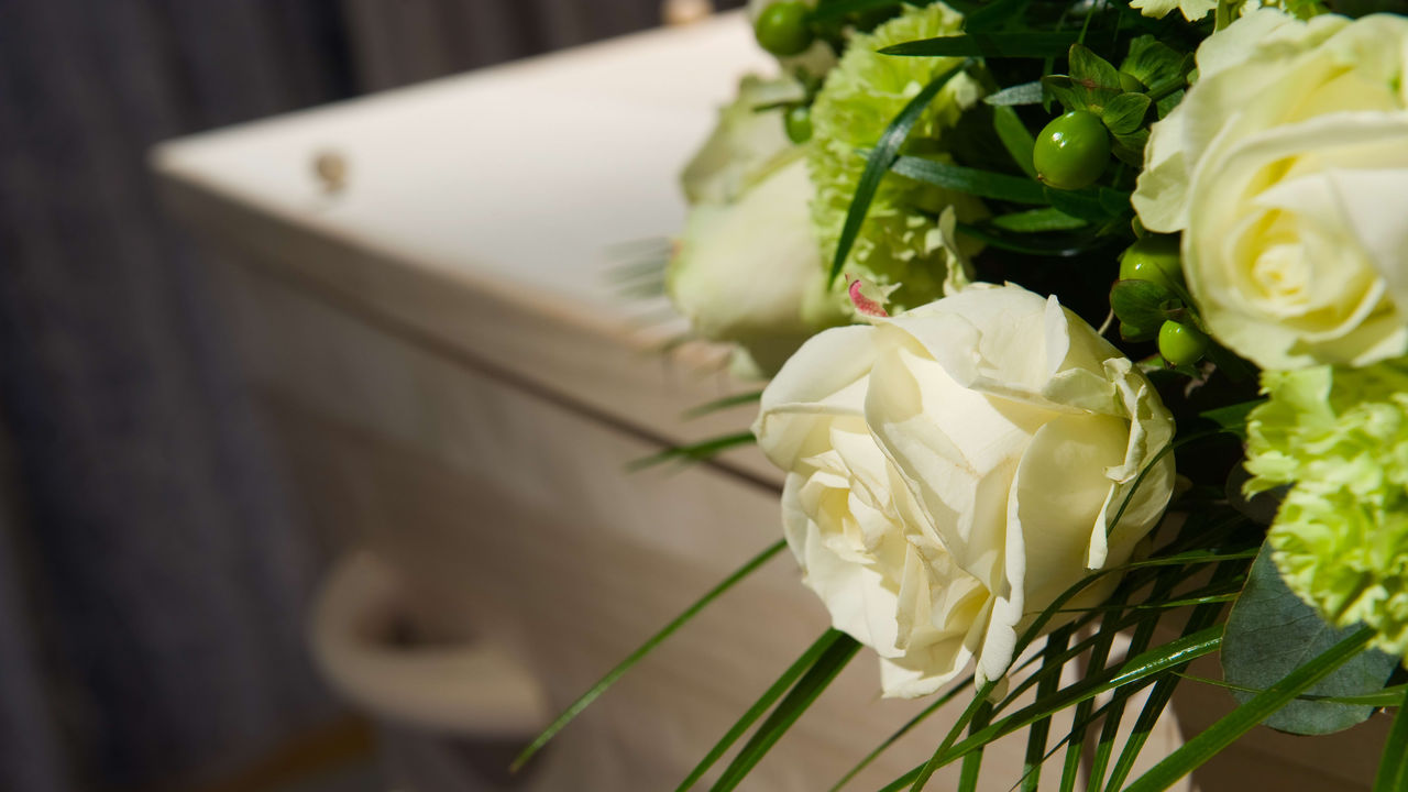 A casket with white flowers and greenery.