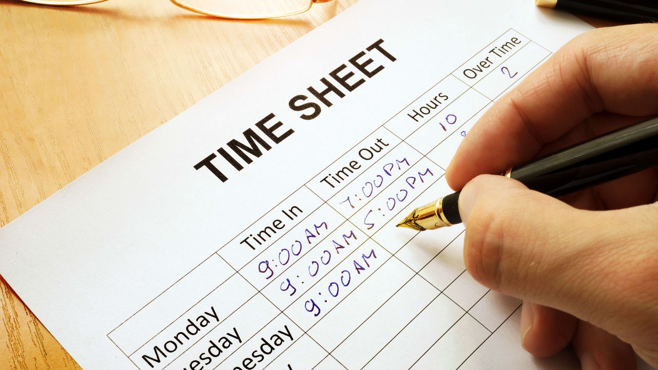 A person writing a time sheet on a piece of paper.