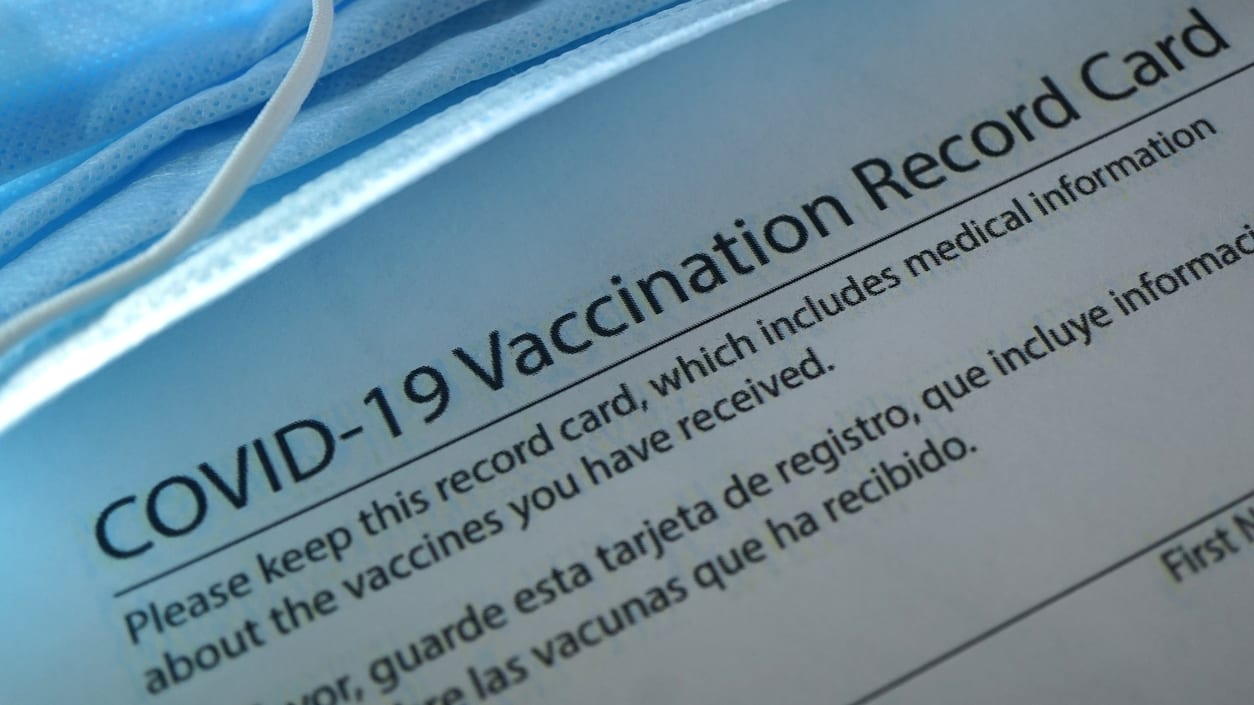 A covid-19 vaccination record card on a sheet of paper.