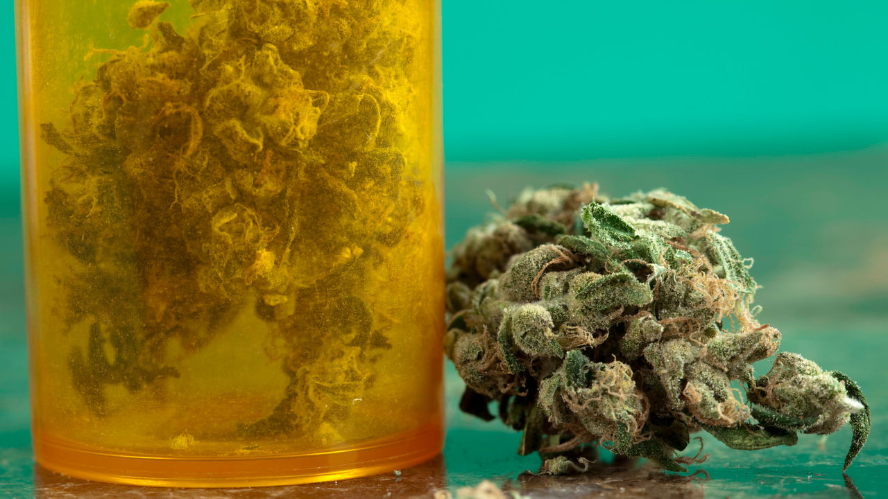 Marijuana in a pill bottle on a table.