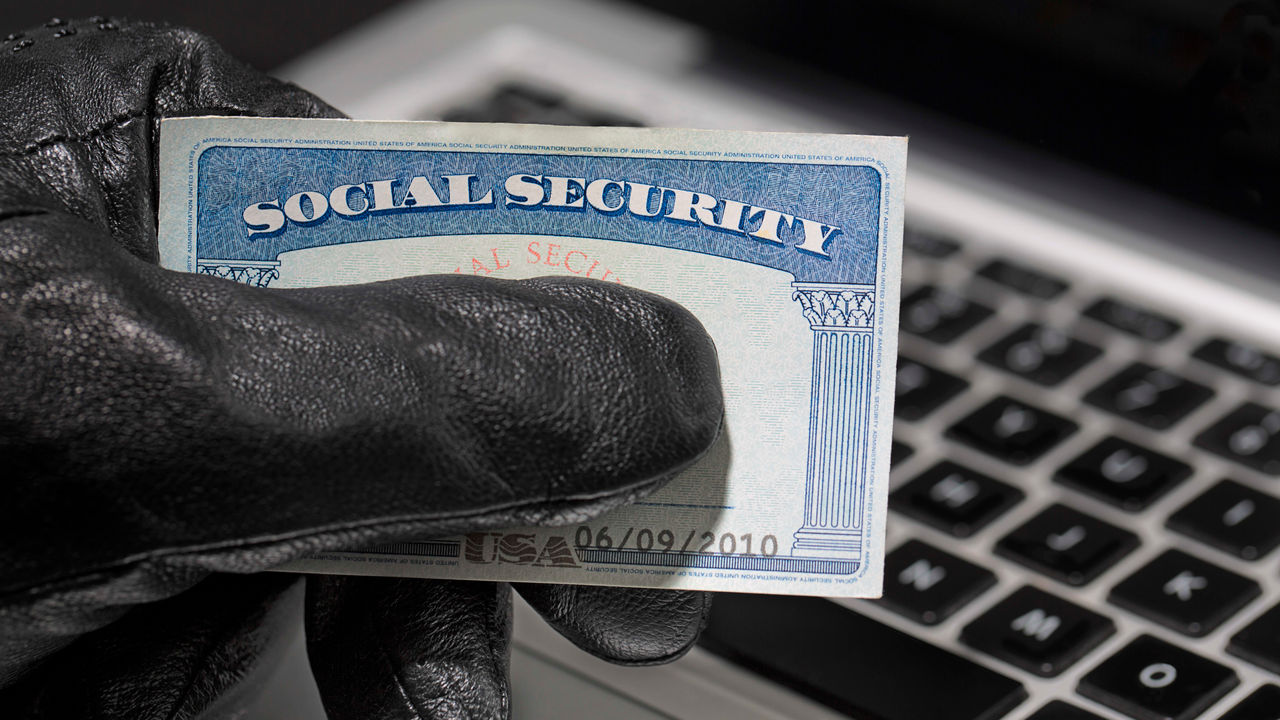 A hand holding a social security card on a laptop.