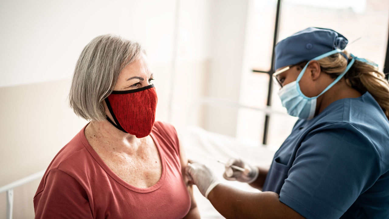 An older woman wearing a face mask in a hospital.