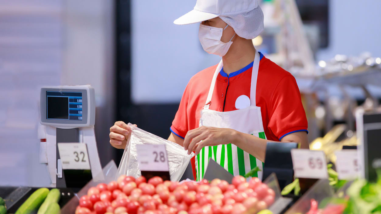 A worker wearing a face mask in a grocery store.