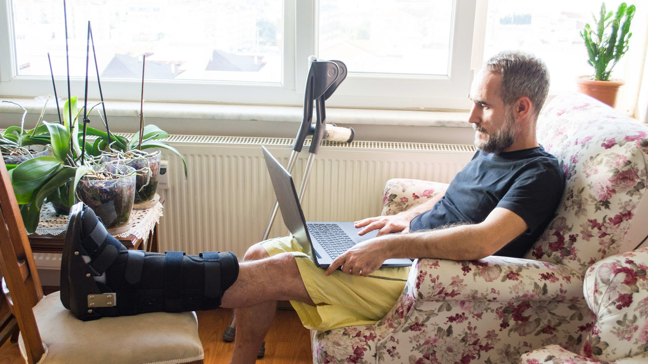 A man using a laptop while sitting in a chair.