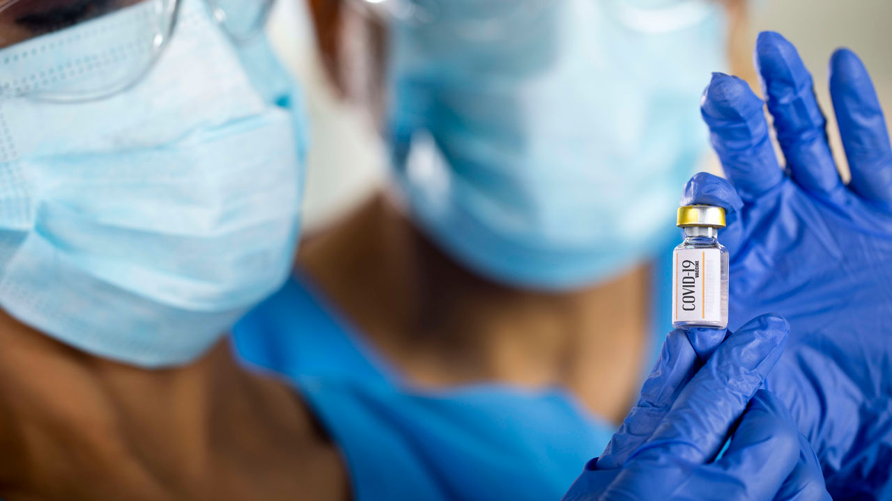 Two nurses holding a bottle of coronavirus vaccine.