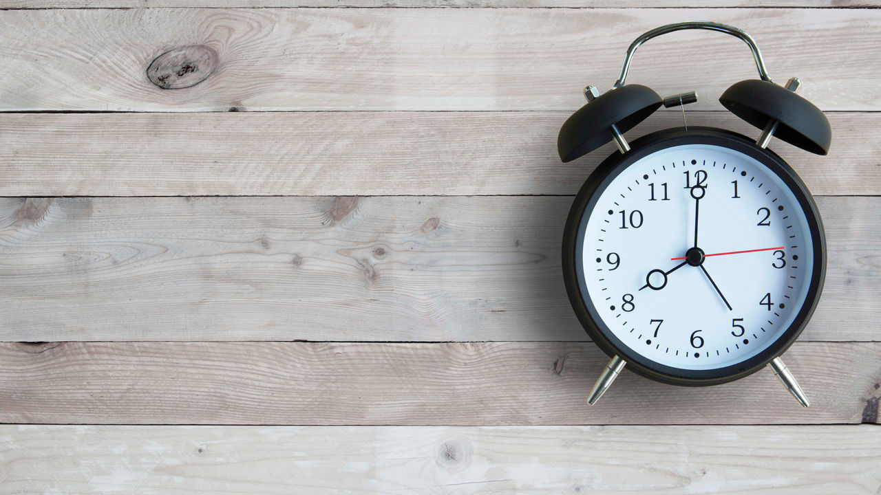 A black alarm clock on a wooden background.