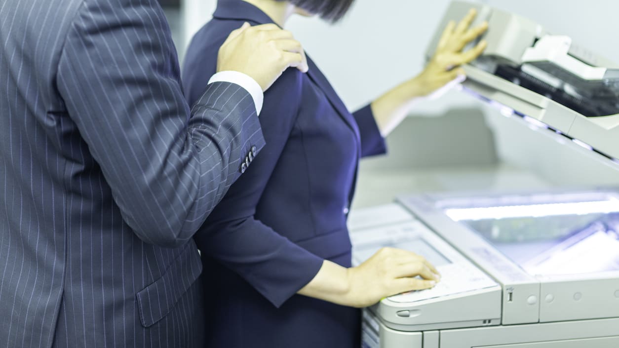 A man and woman standing next to a printer.