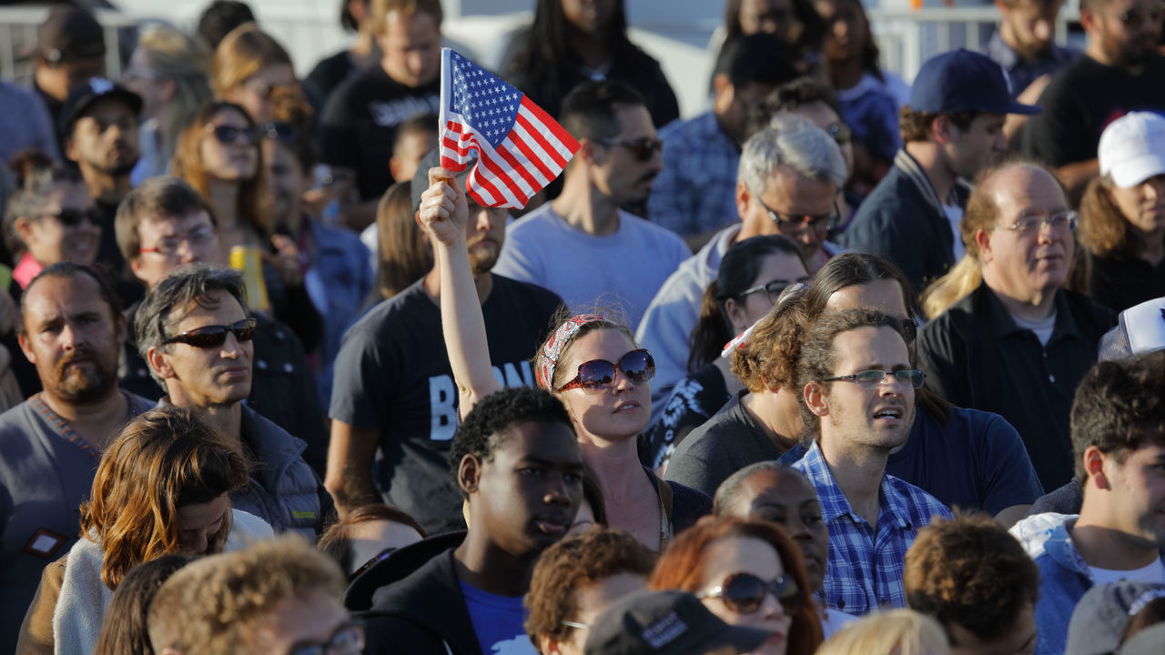 A crowd of people holding an american flag.