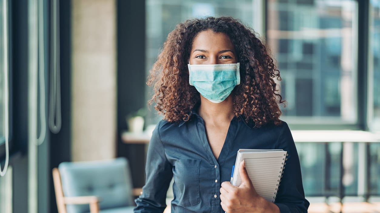 A woman wearing a surgical mask in an office.