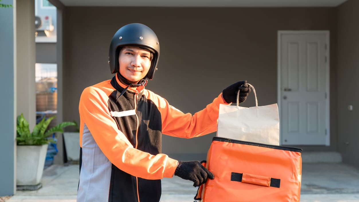 A man holding a delivery bag on a motorcycle.