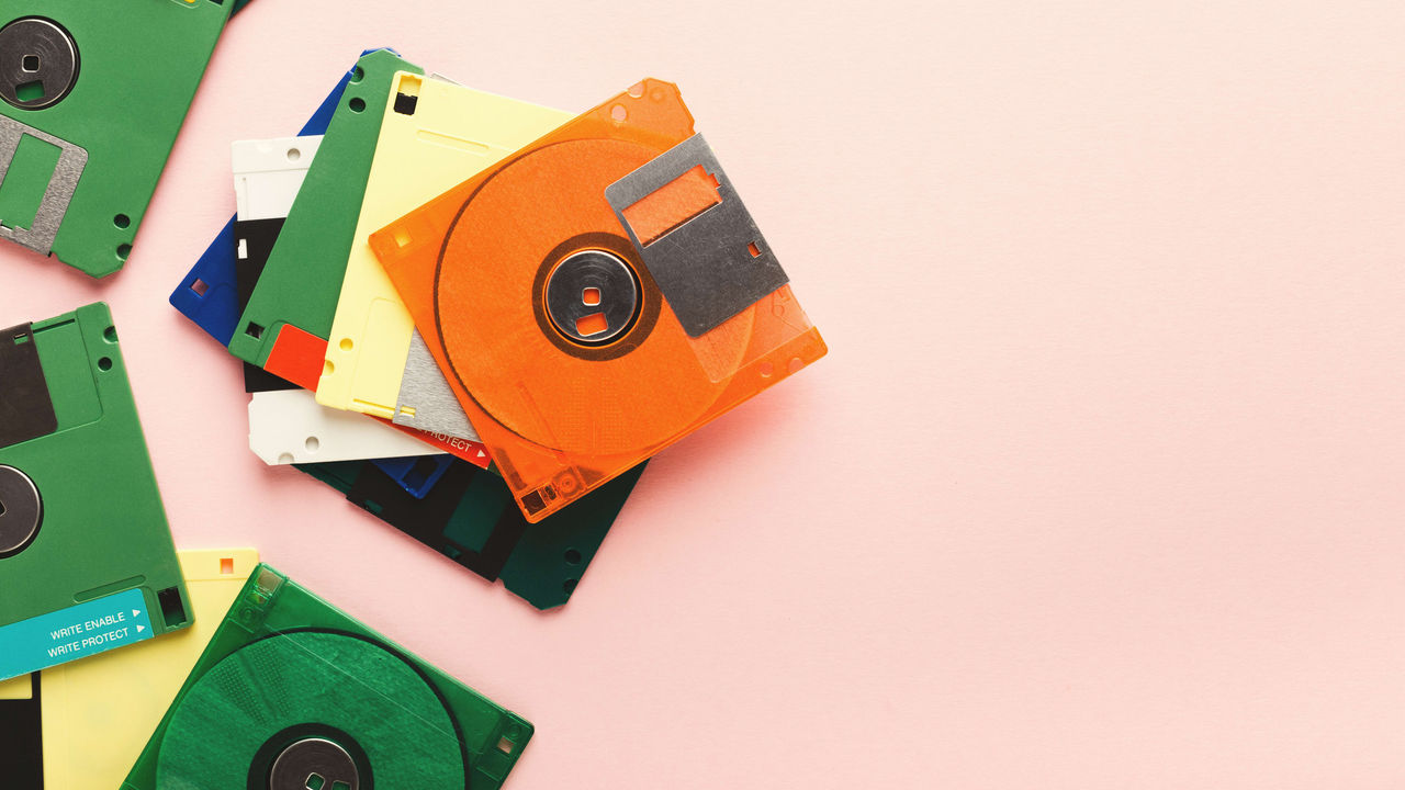 Colorful floppy disks on a pink background.