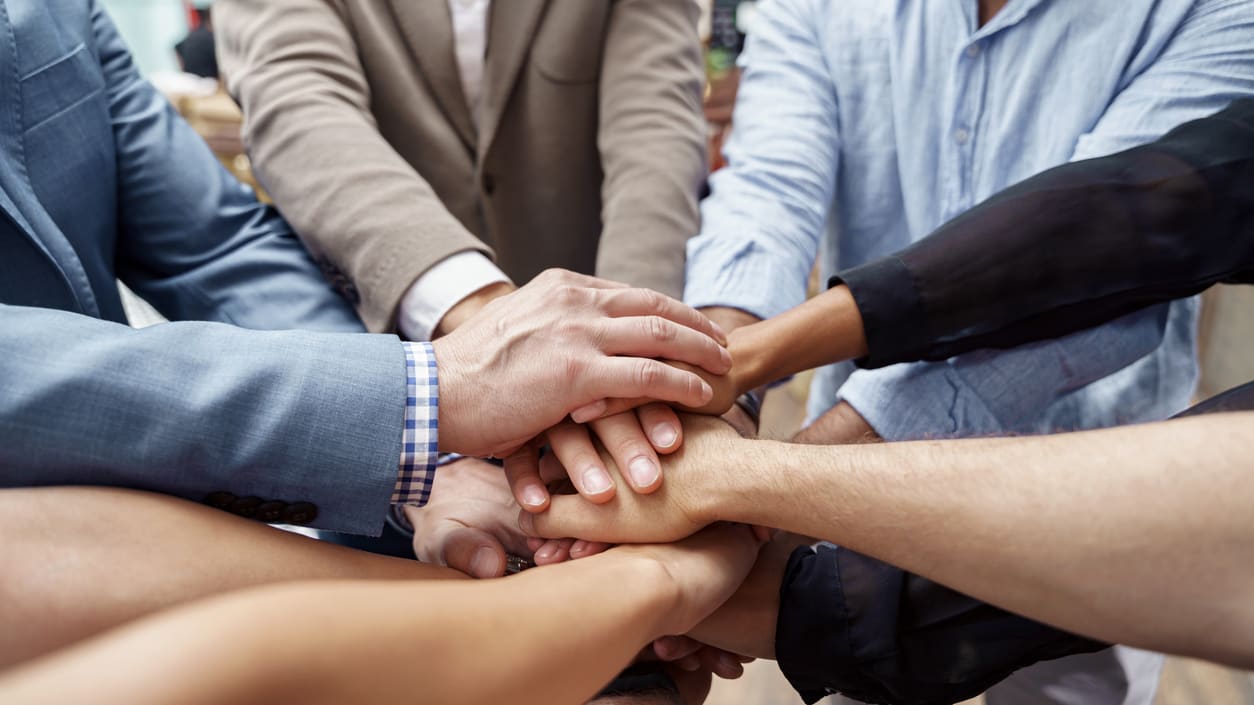 A group of business people putting their hands together.