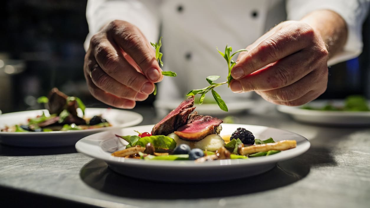 A chef is preparing a plate of food in a restaurant.