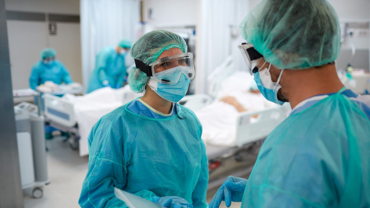 Two doctors in scrubs talking to each other in a hospital.