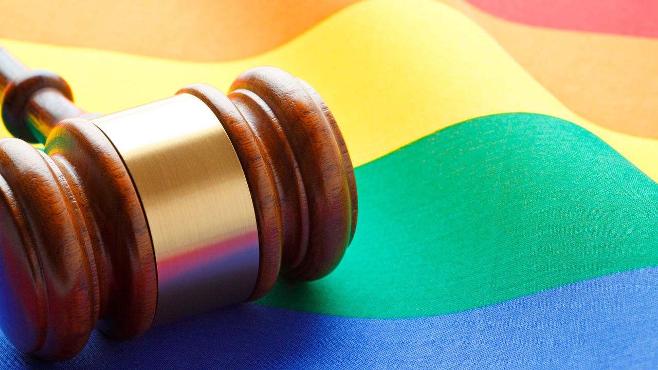 A gavel sits on top of a rainbow flag.