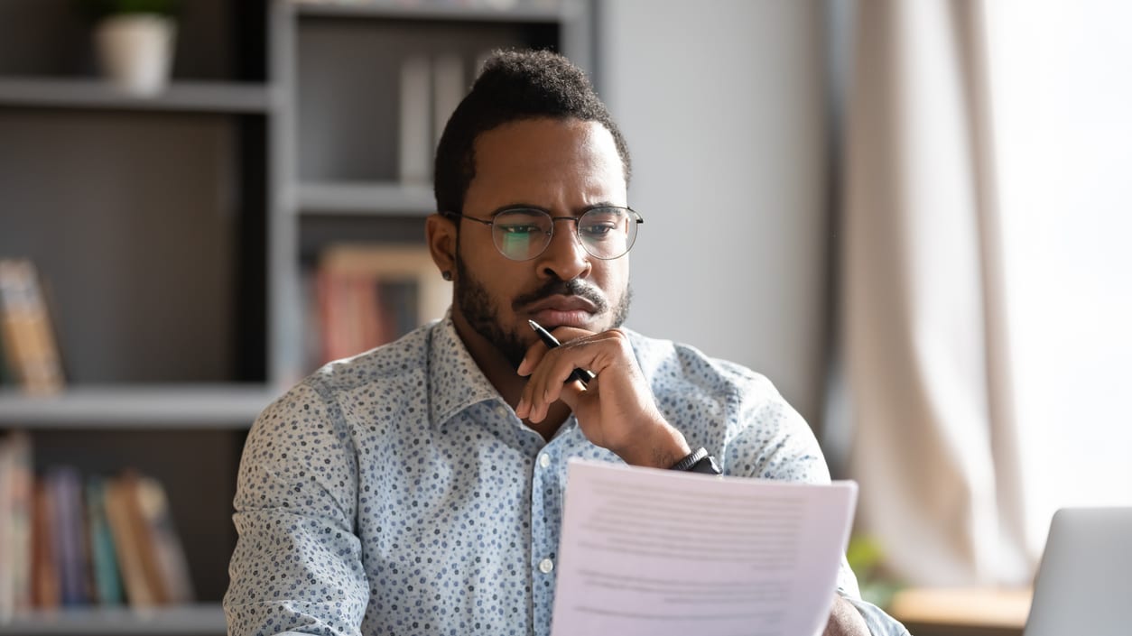 A man sitting at a desk looking at a piece of paper.
