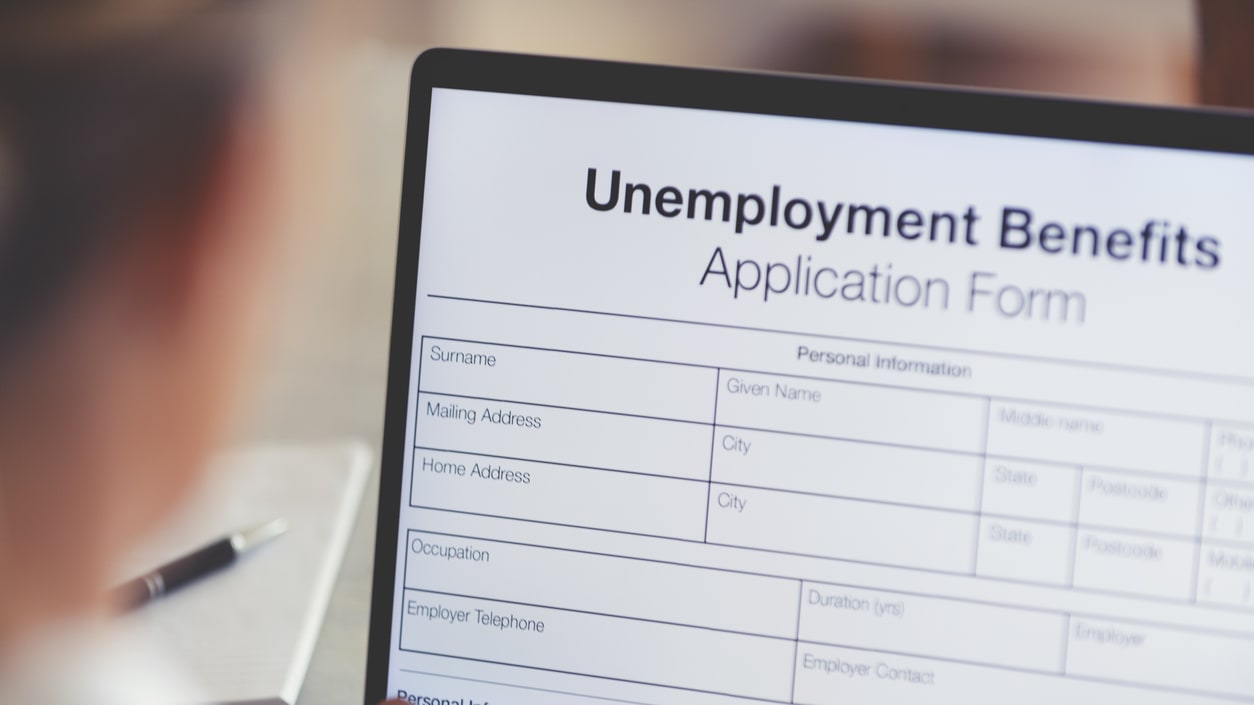 A woman is using a laptop to fill out an unemployment benefits application form.