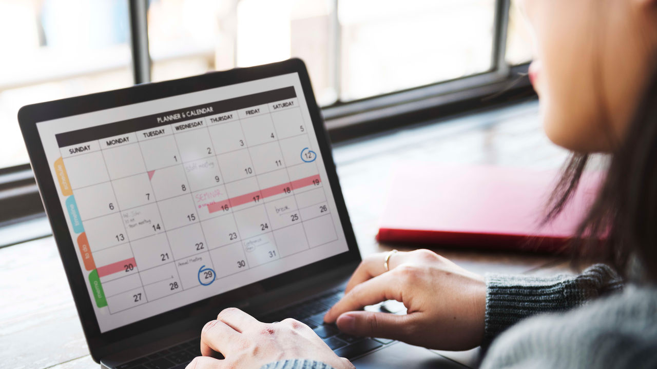 A woman is using a laptop with a calendar on it.