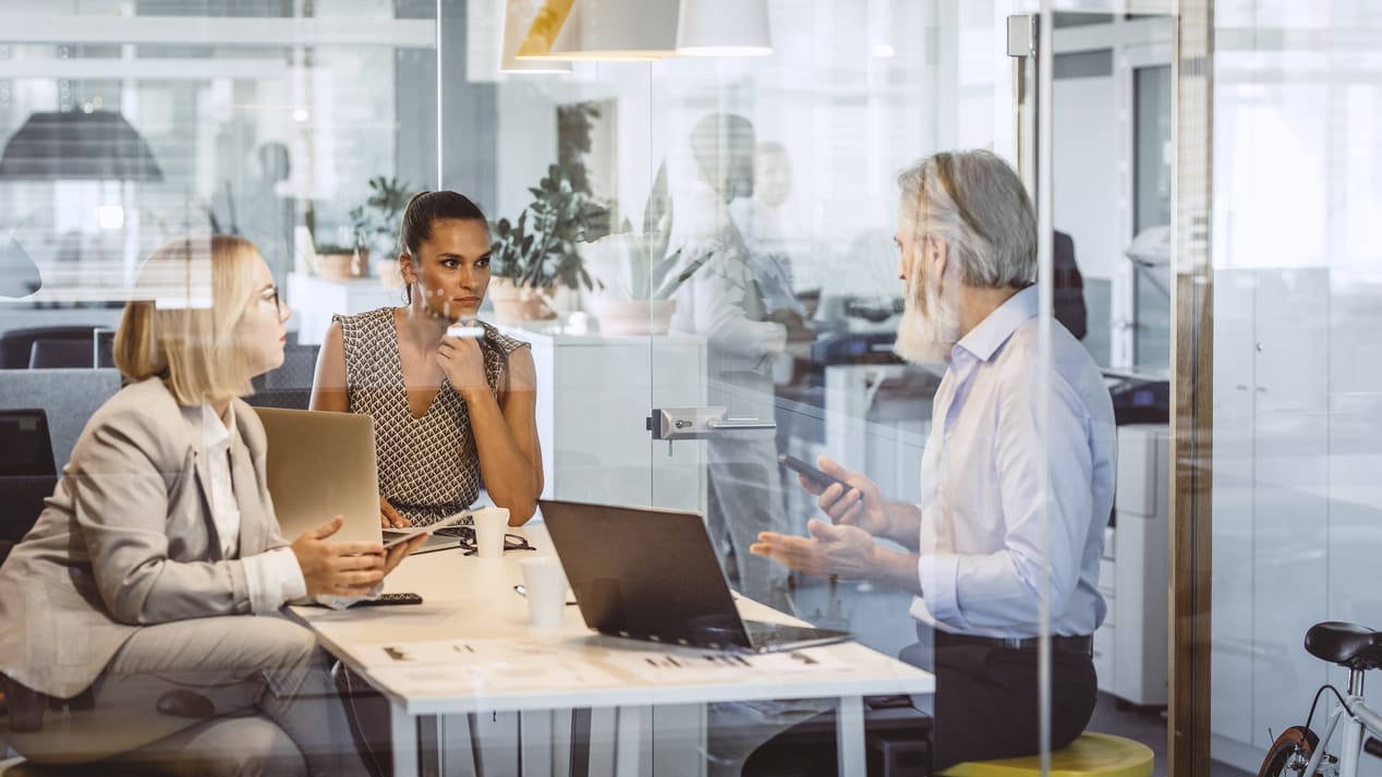 A group of people sitting at a table in an office.