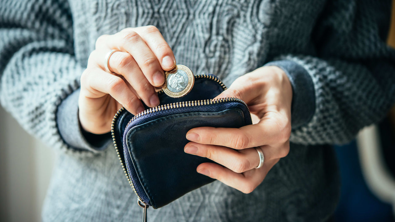 A woman is holding a coin in her purse.