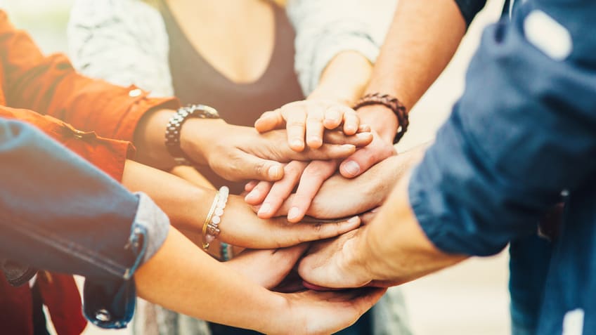 A group of people putting their hands together in a circle.
