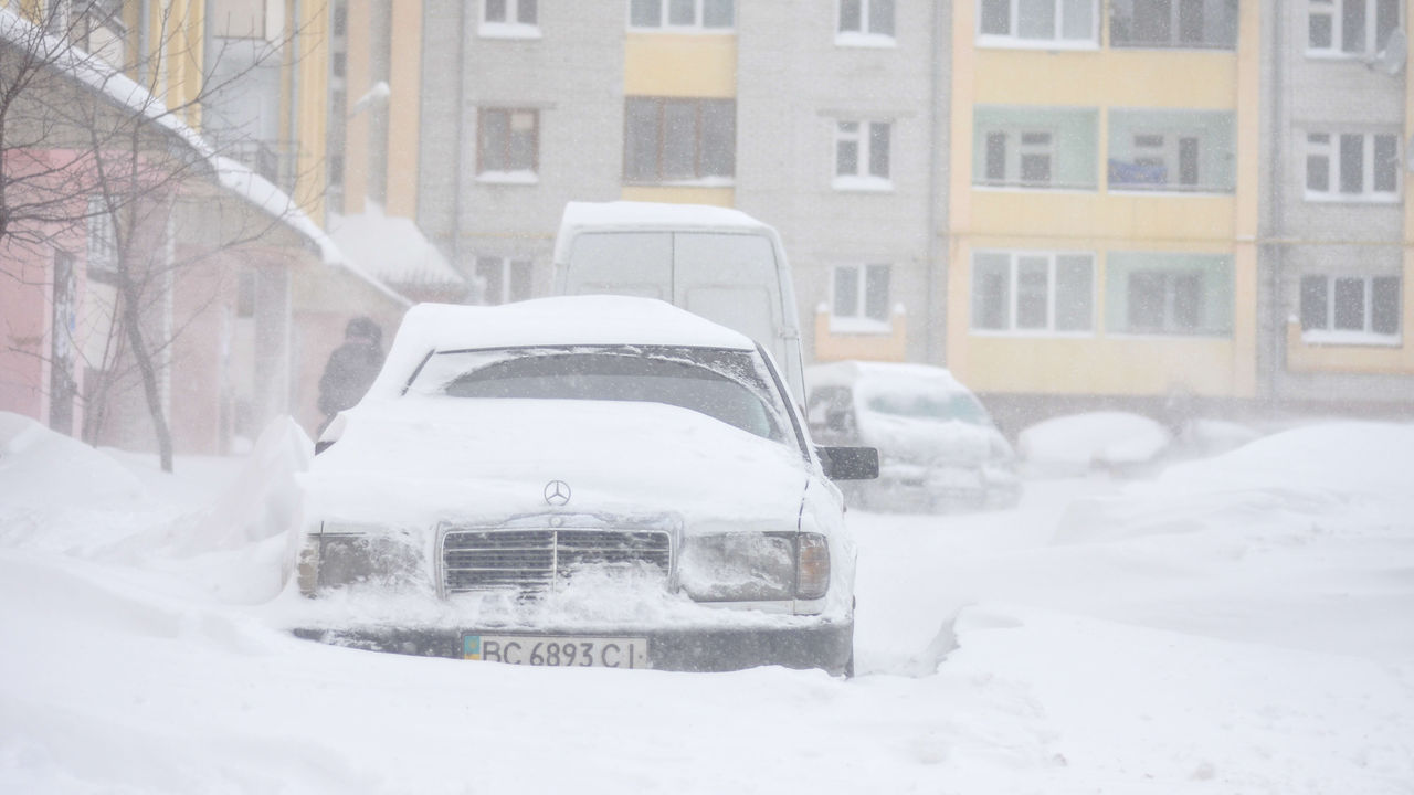 A car is parked in a snow covered street.