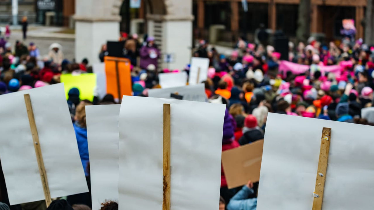 A crowd of people holding signs in front of a building.