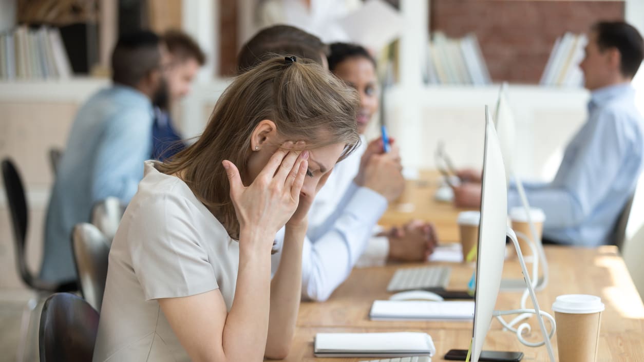 A group of people sitting at a desk in an office.