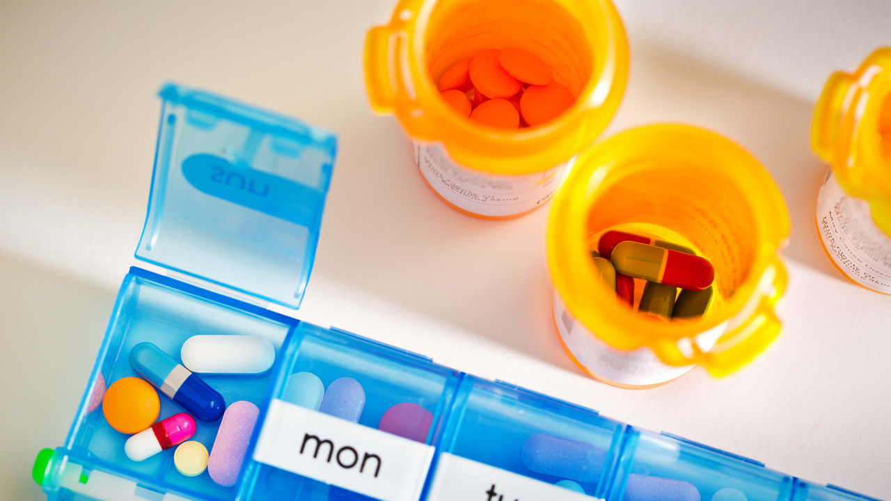 A blue pill box filled with pills and a calendar.