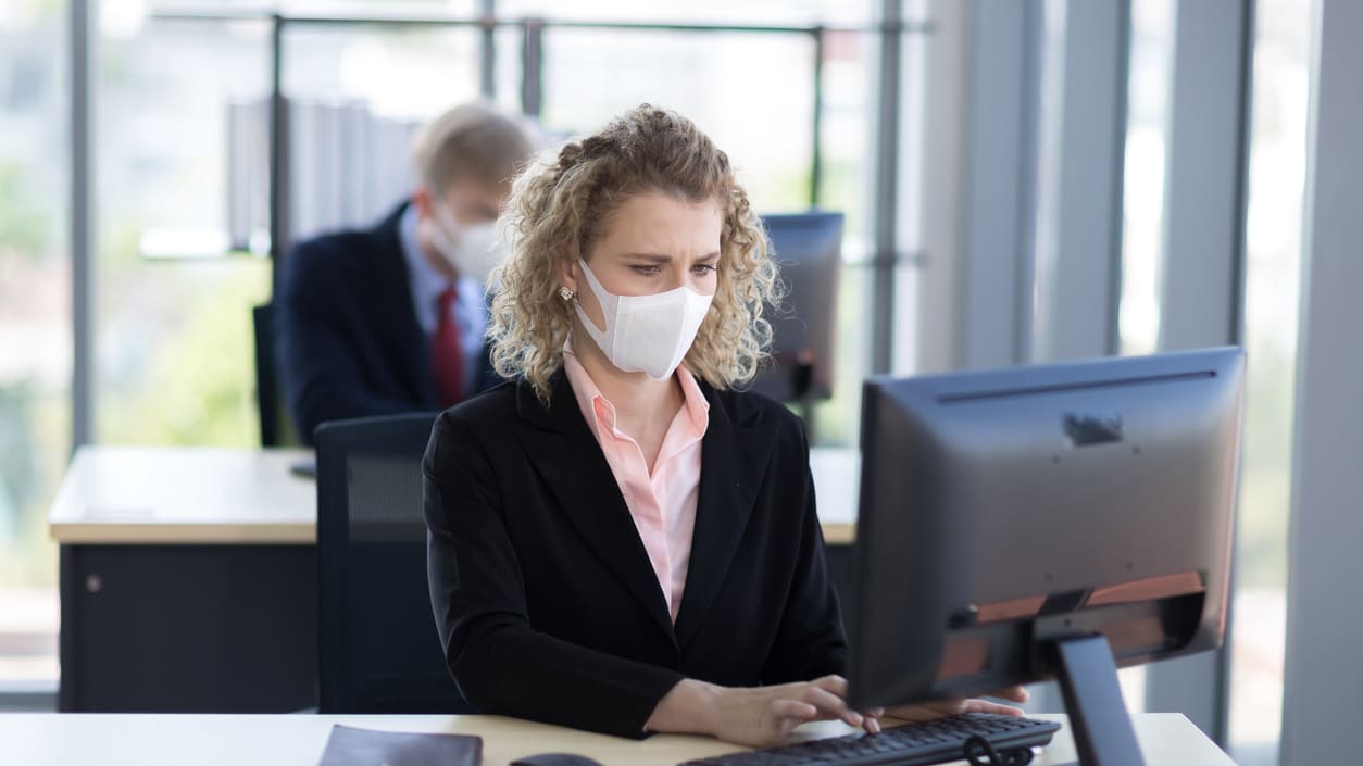 A woman wearing a face mask while working in an office.