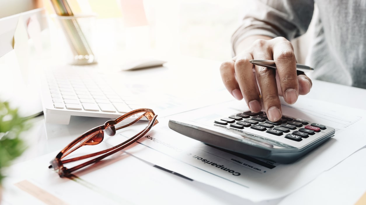 A person is using a calculator on a desk.