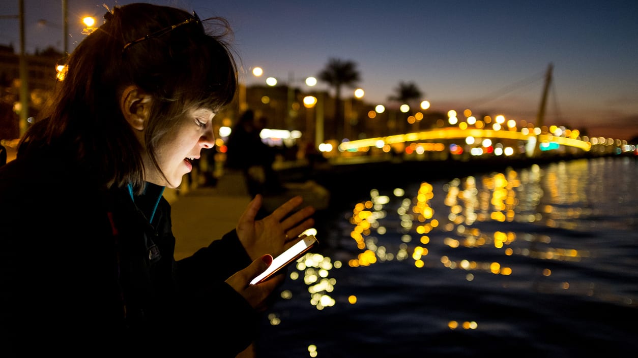 A woman looking at her cell phone at night.