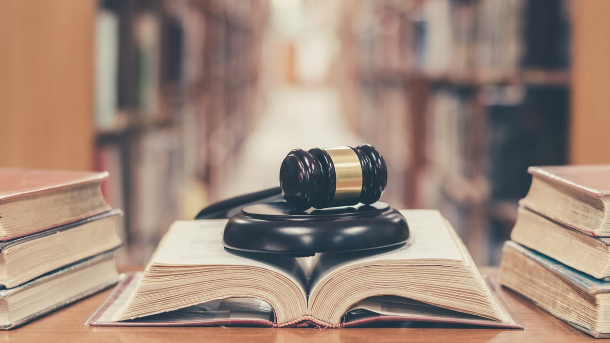 A judge's gavel sits on top of books in a library.