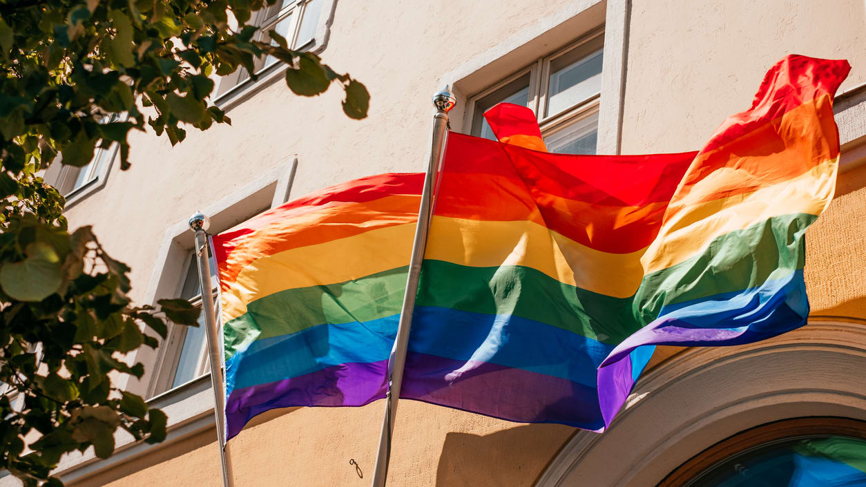 Two rainbow flags flying in front of a building.