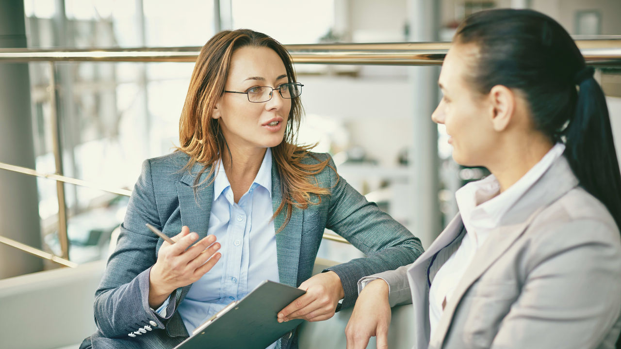 Two business women talking to each other in an office.