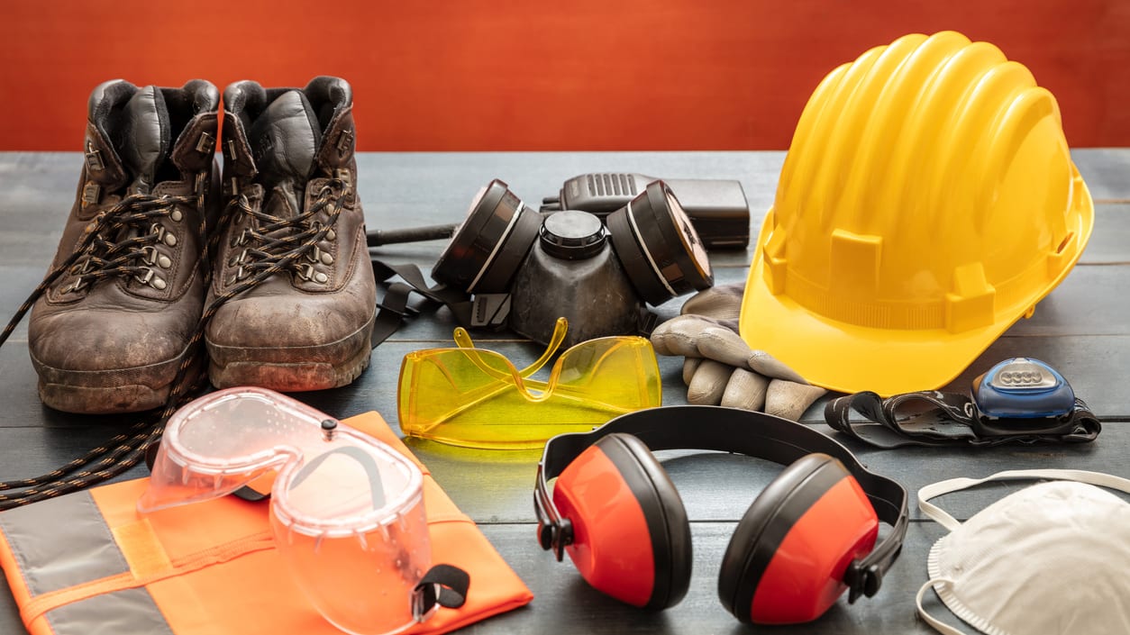 A table with safety equipment including a hard hat, safety glasses, and safety goggles.