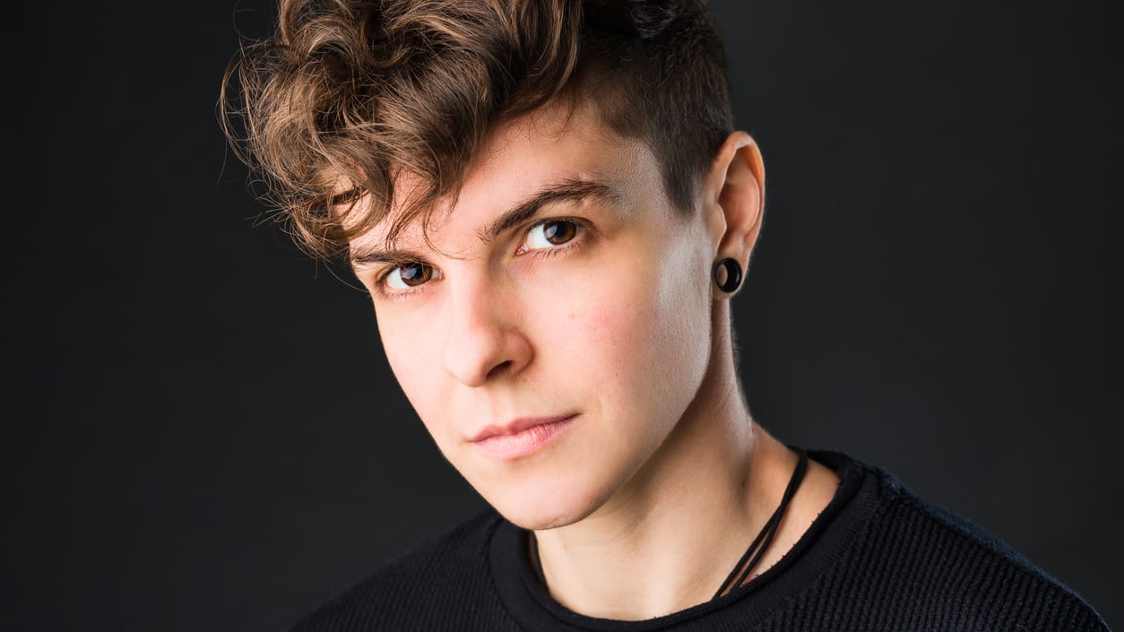 A young man with curly hair is posing for a photo.