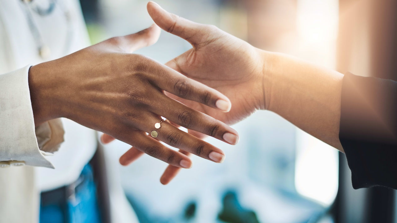 Two people shaking hands in front of a window.