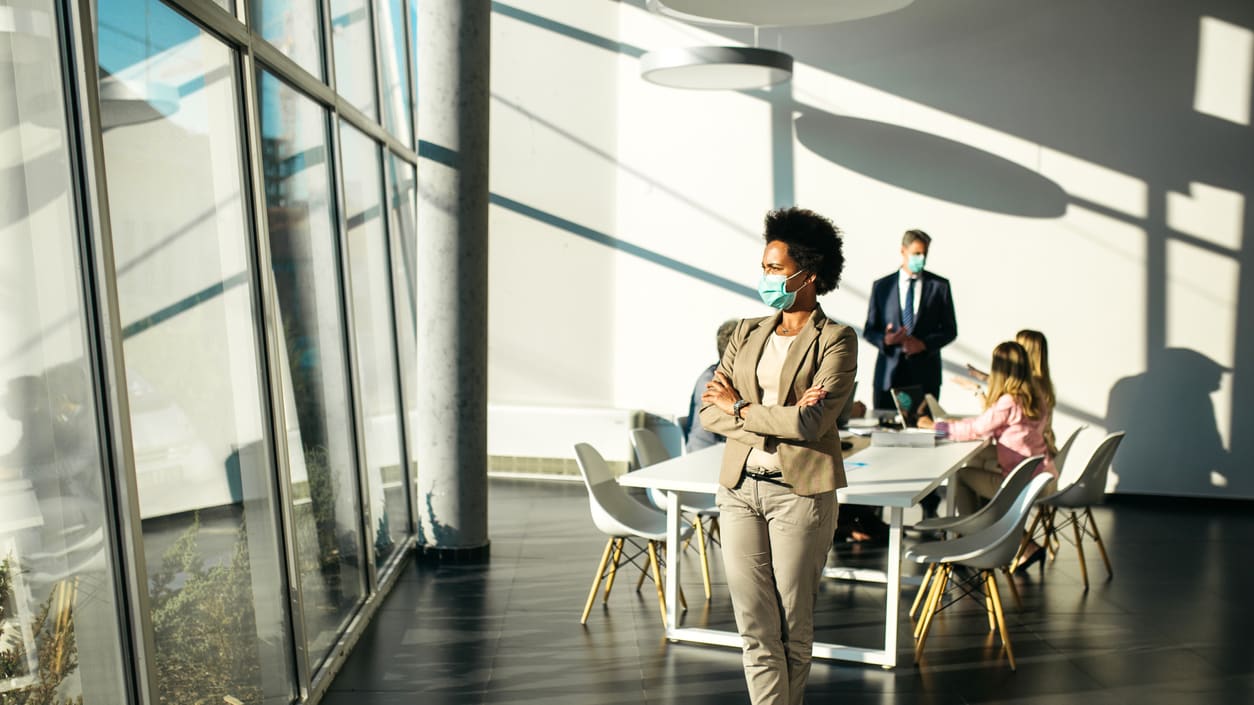 A business woman wearing a face mask in a conference room.