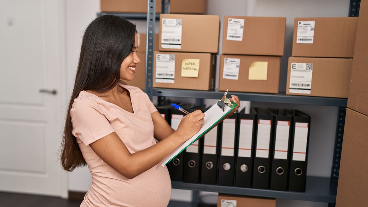 A pregnant worker filling out paperwork on a clipboard