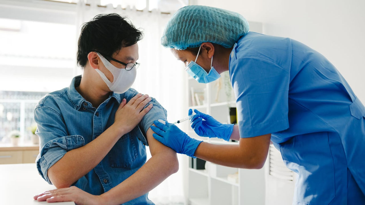 A man is getting his arm vaccinated by a doctor.