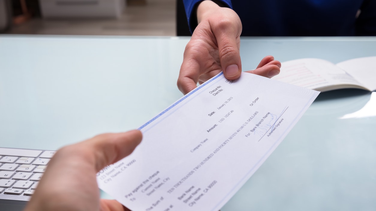 A person handing a check to another person in an office.