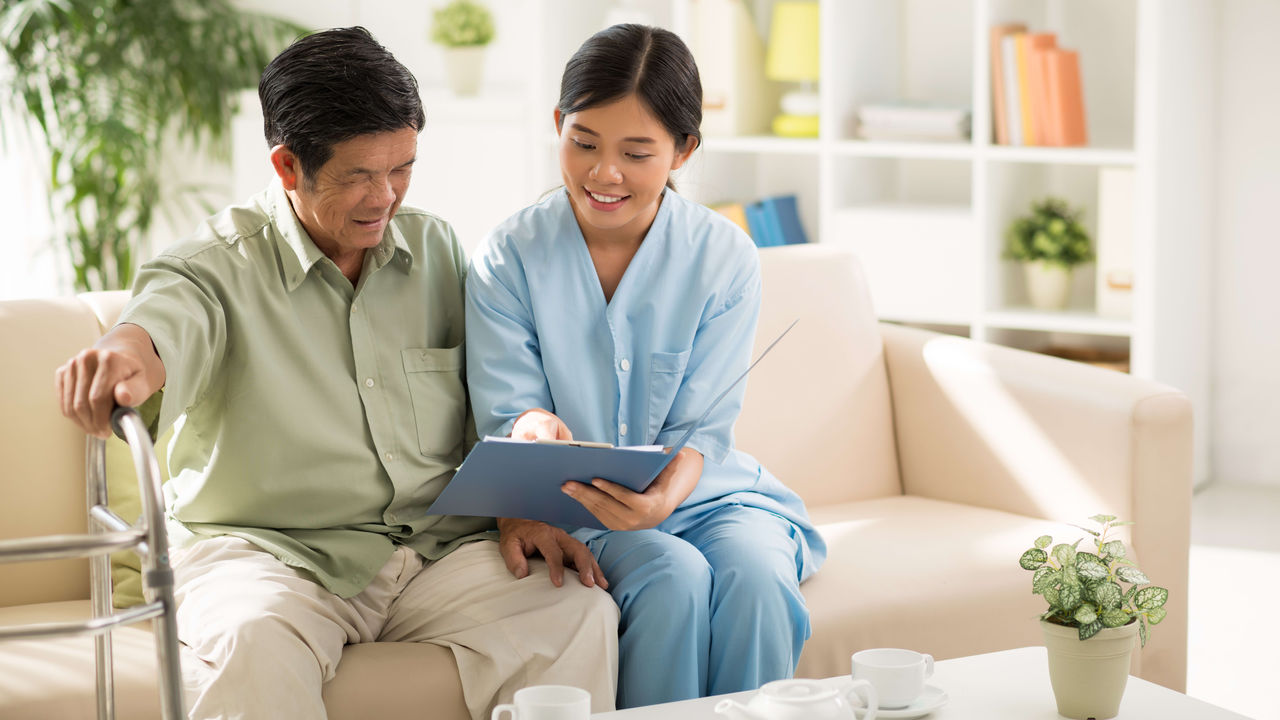 An asian couple looking at a tablet while sitting on a couch.