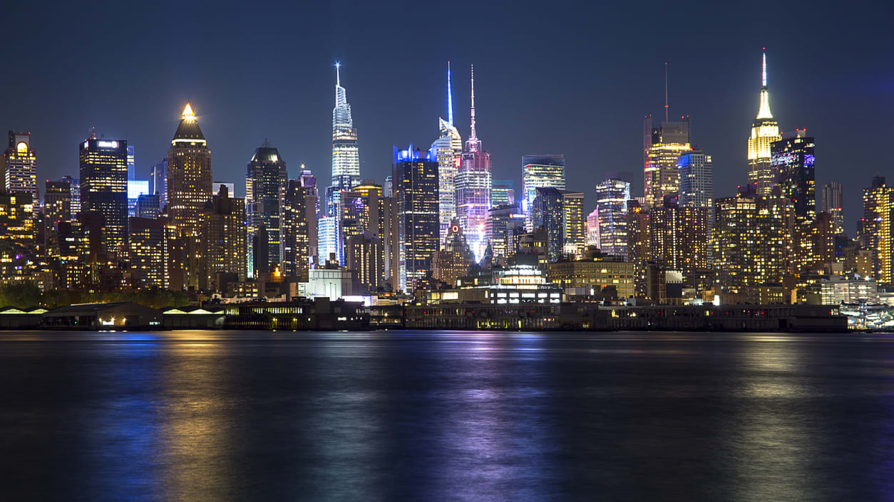 The manhattan skyline is lit up at night.