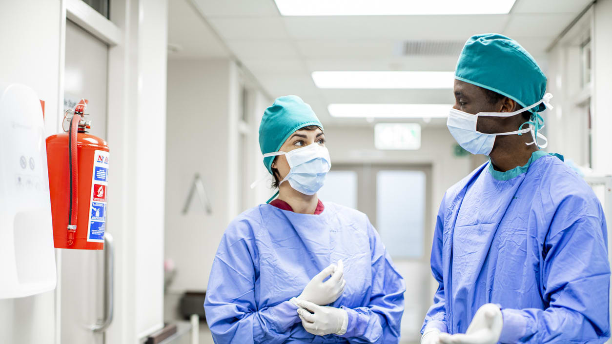 Two surgeons talking in a hospital corridor.